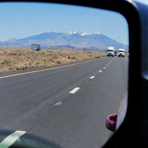 Mountains in the rearview mirror of a jeep.