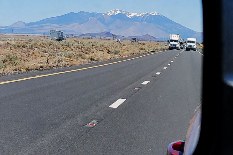 Mountains in the rearview mirror of a jeep.